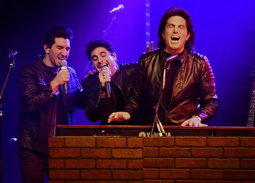 The Bronx Wanderers performing on stage, with Vinny Adinolfi as the central frontman holding a microphone.