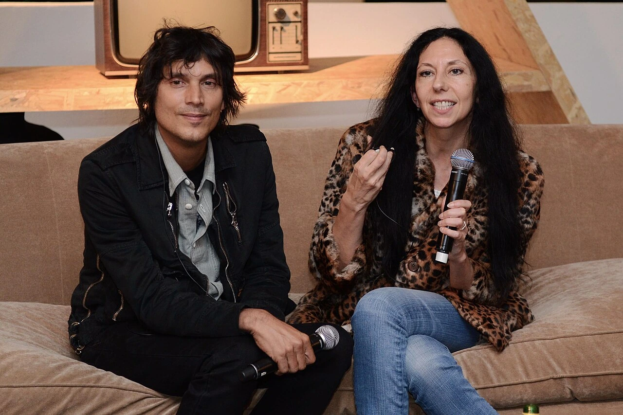 Inez van Lamsweerde and Vinoodh Matadin seated together during a public appearance, each holding a microphone.